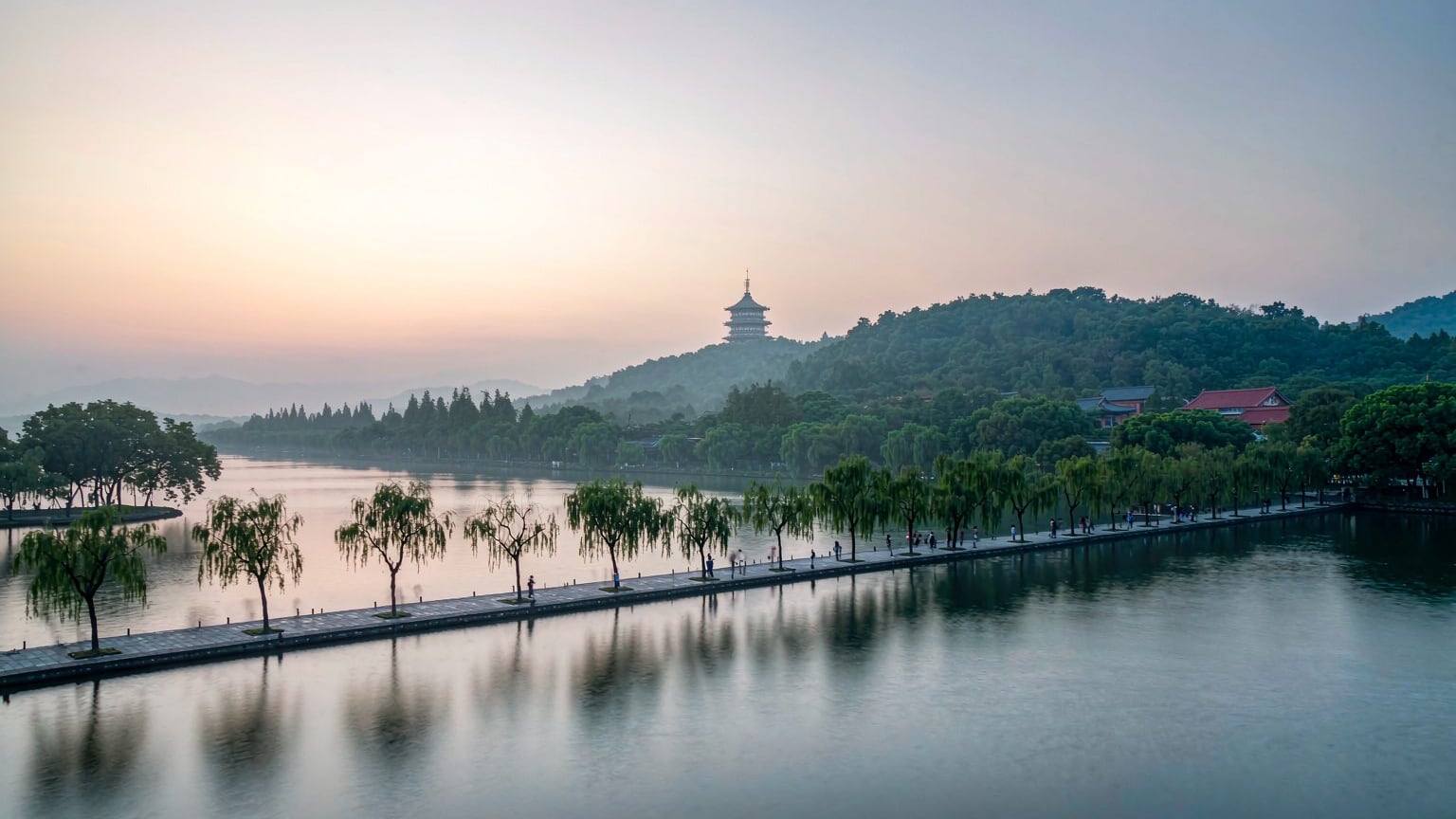 West Lake in Hangzhou with a pagoda and willow-lined causeway at dawn
