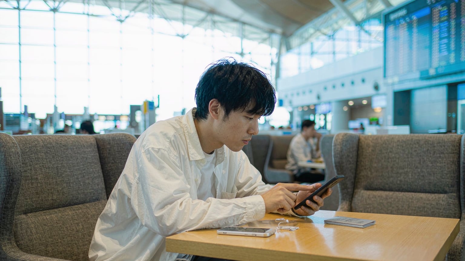 A traveler checking a map app on their phone at an airport café in China, a local SIM card on the table